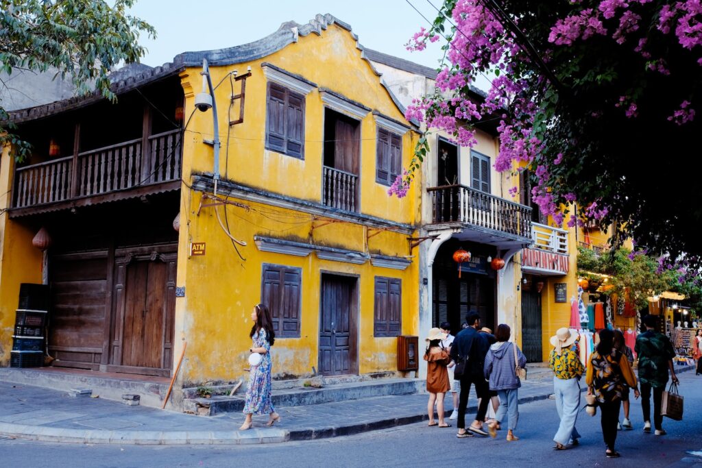 people walking on sidewalk near yellow concrete building during daytime